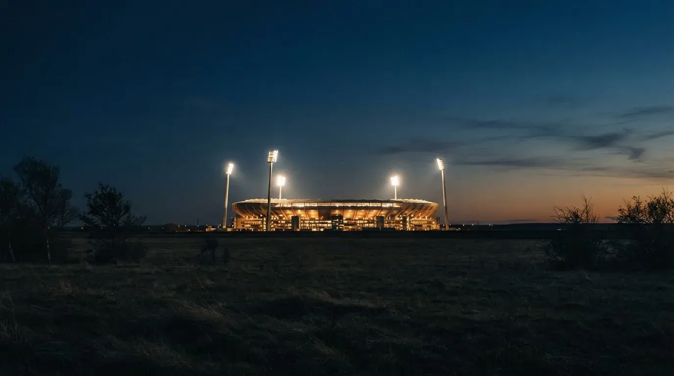 Ein Stadion unter Flutlicht aus großer Entfernung gesehen, der Himmel darüber ist tiefblau.