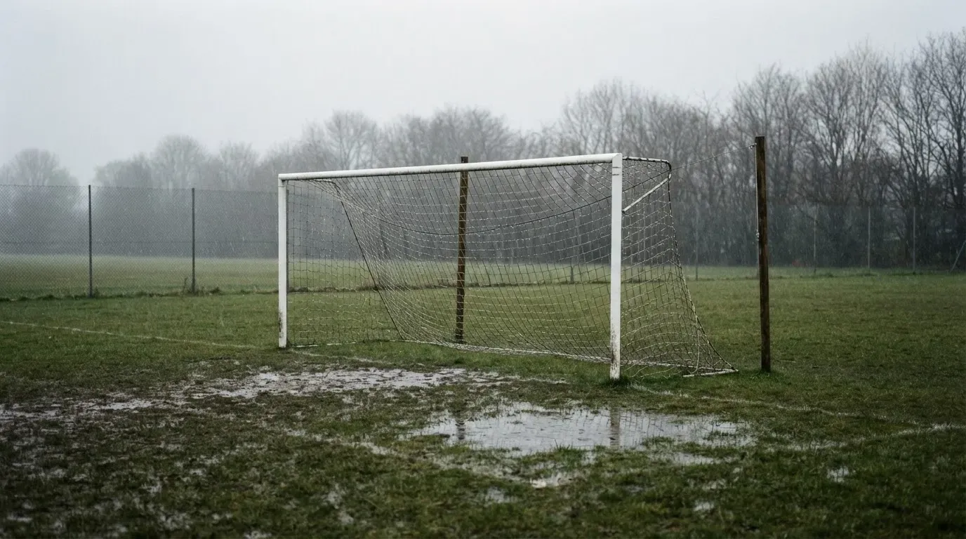 Ein Fußballtor mit Netz auf einem Trainingsplatz bei Regen, Pfützen stehen auf dem Rasen, niemand ist zu sehen.